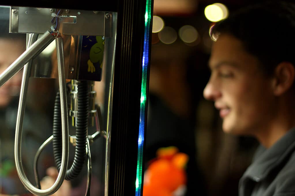 photo of man in front of claw machine